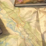 Mapa turystyczna, laptop i notes podczas planowania wyprawy.