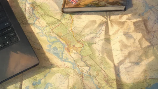 Mapa turystyczna, laptop i notes podczas planowania wyprawy.