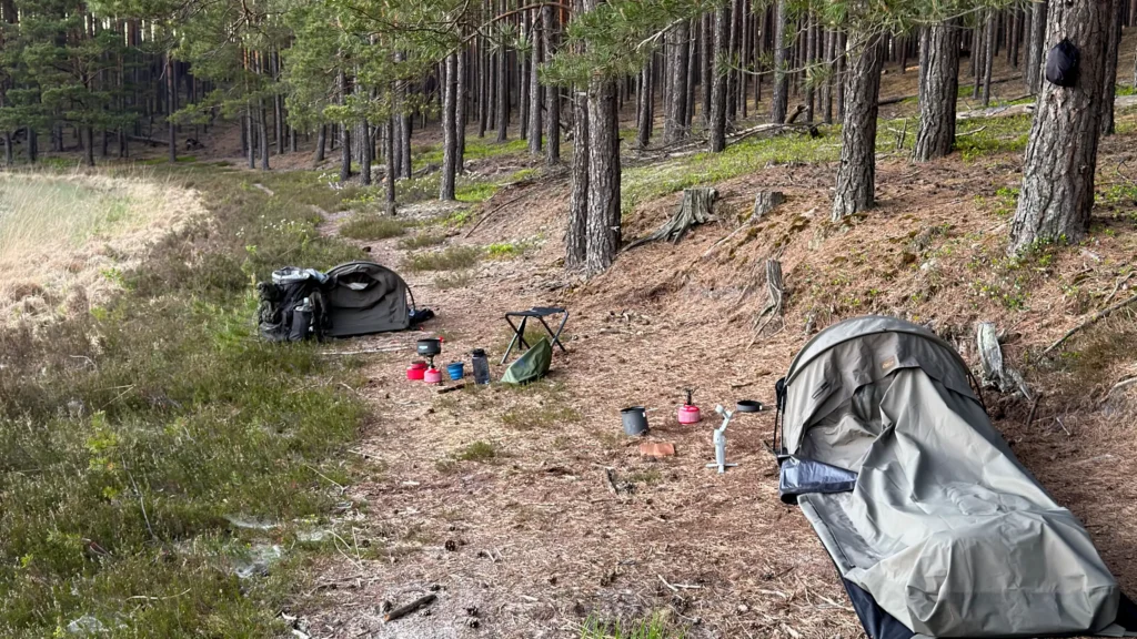 Bivi Bag Carinthia Observer Plus rozłożone nad jeziorem o zachodzie słońca.