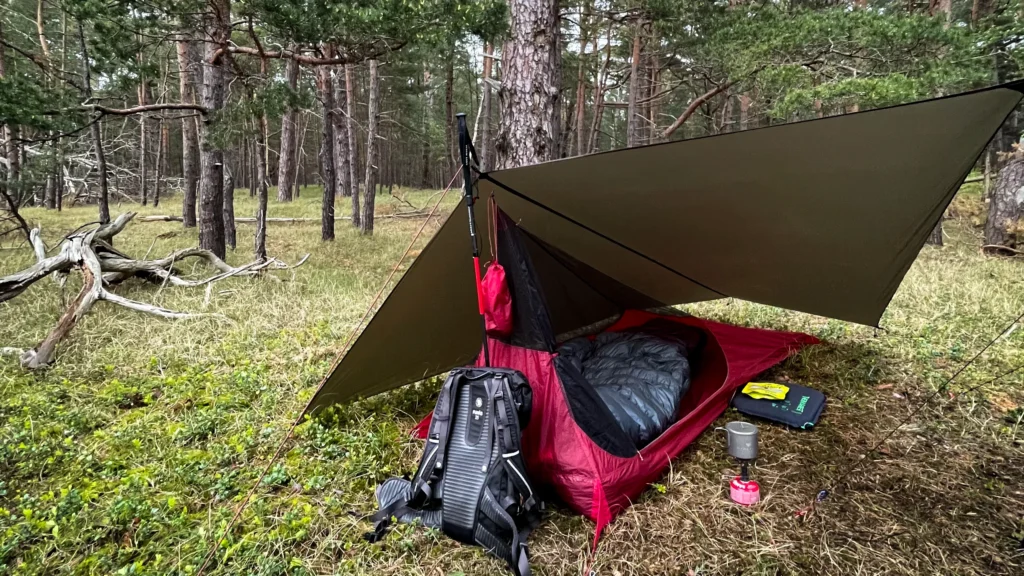MSR Hiker House z wyposażeniem biwakowym ustawiony pod tarpem w lesie.