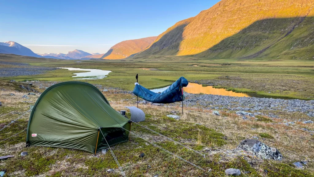 Namiot Fjallraven i śpiwór Therm-a-Rest Hyperion podczas biwaku w górskiej dolinie.